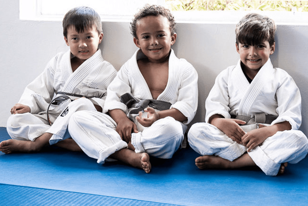 Toddlers children sitting in a line wearing white gis