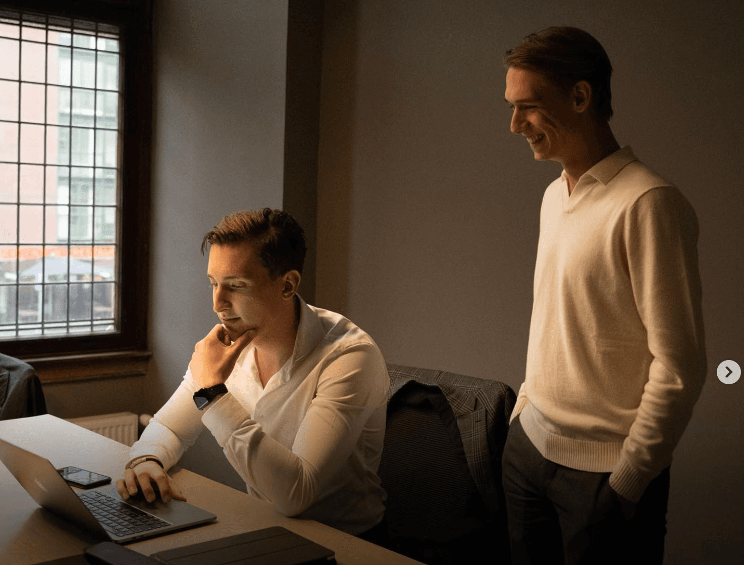 A large group photo of diverse team members gathered in an industrial-style space with arched ceiling.