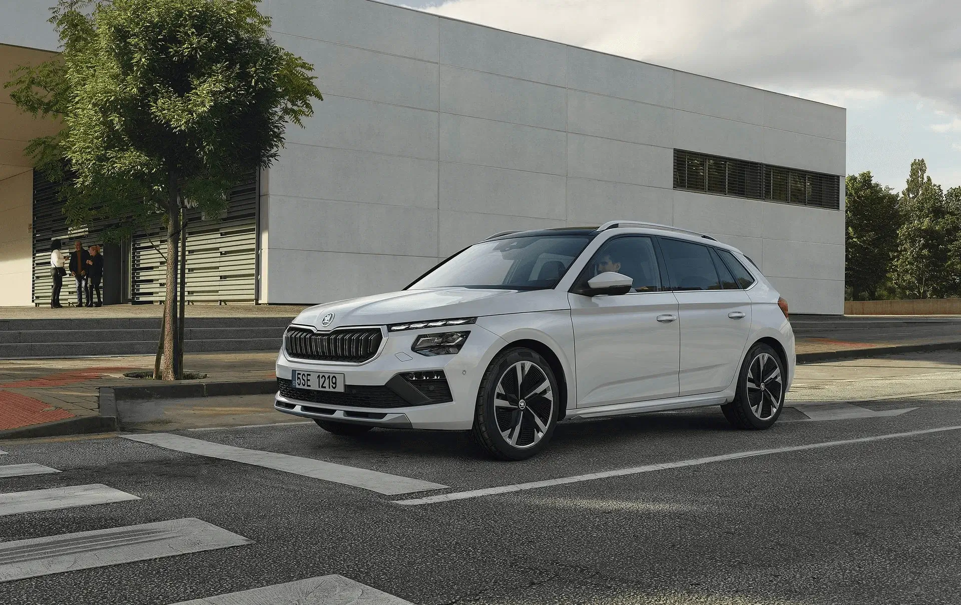 Modern indoor space with large glass doors, lush greenery, and a cozy seating area visible beyond.
