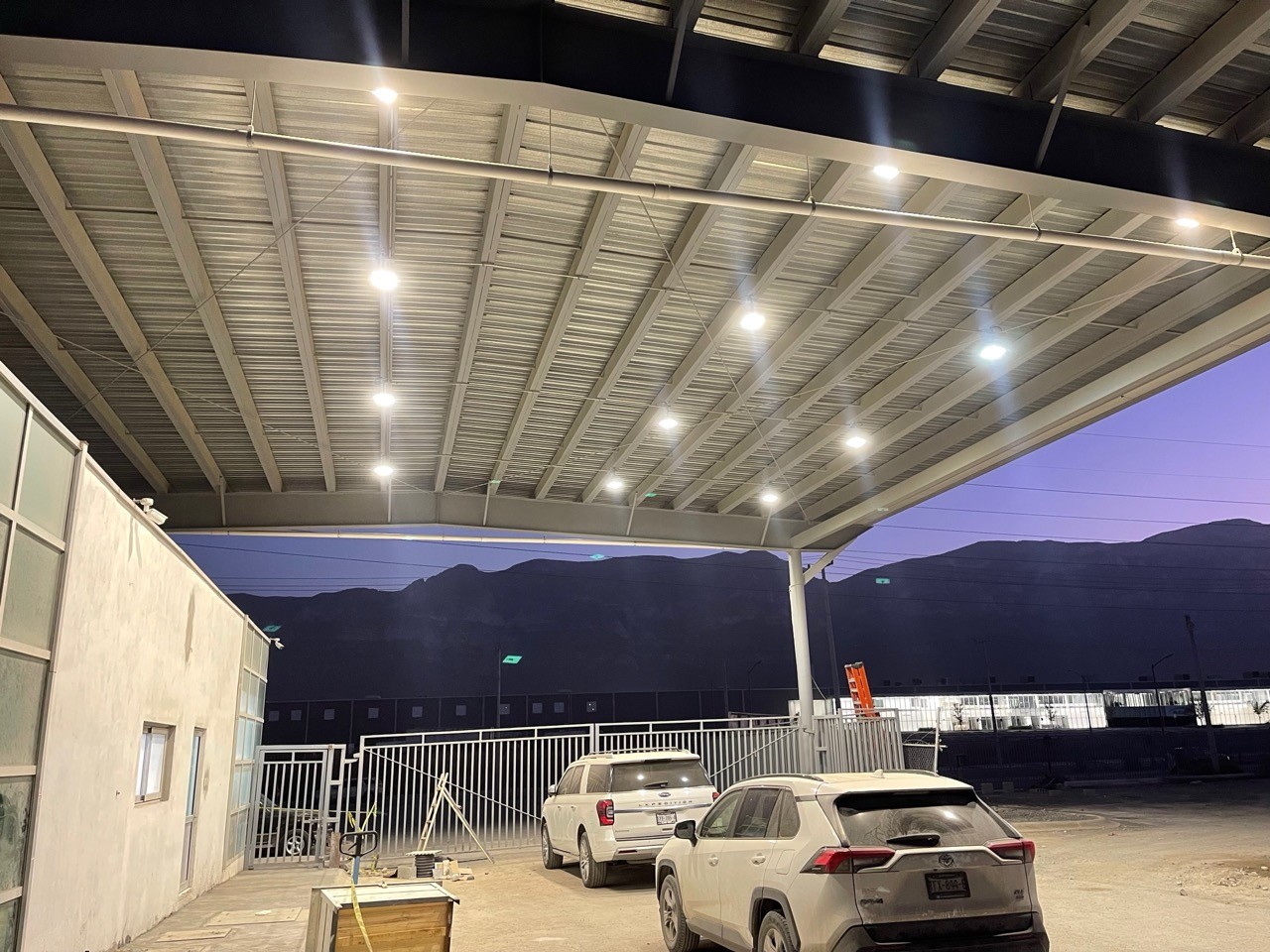 Evening view of steel‑roof industrial shelter, LED high bay lights installed on metal roof truss