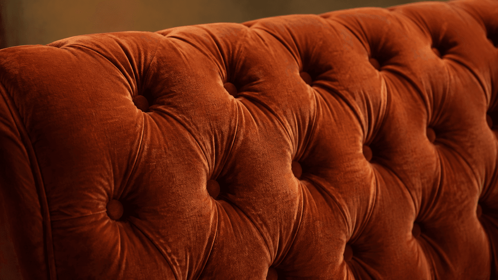 Gros plan sur le capitonnage d’un canapé en velours orange.