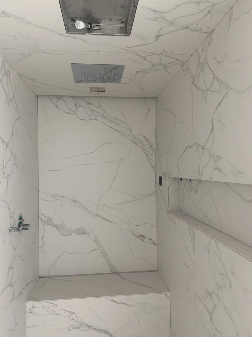 Natural stone shower wall cladding with marble panels and clean bathroom installation finish.