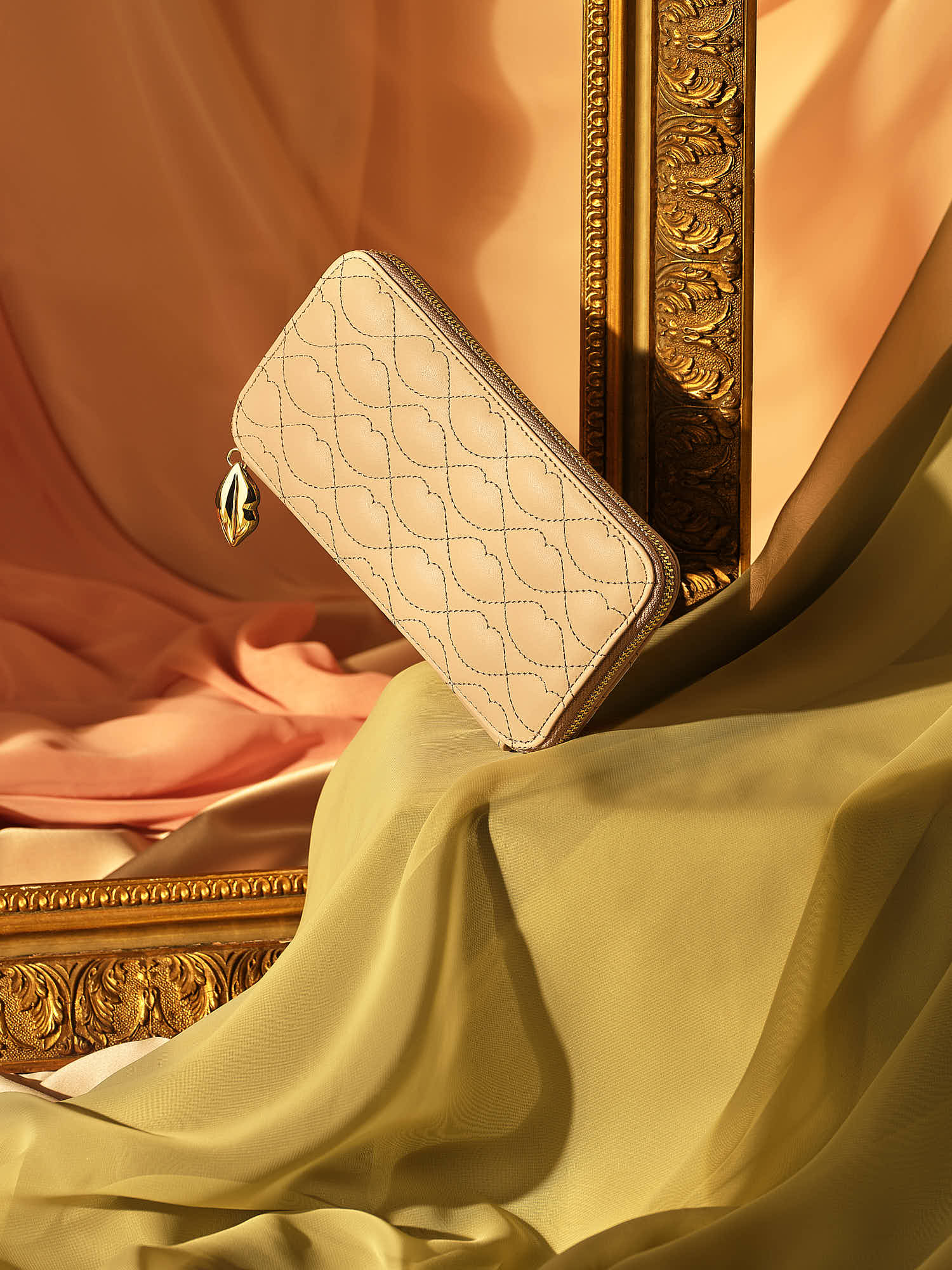 Elegant quilted beige wallet with gold zipper on luxurious fabric background.