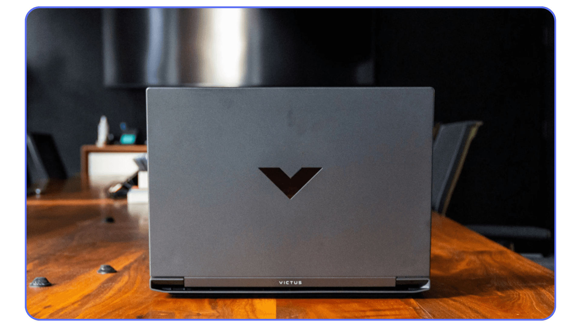 HP Victus gaming laptop closed view – HP Victus laptop on a wooden desk, photographed from the back with the distinctive V logo visible.
