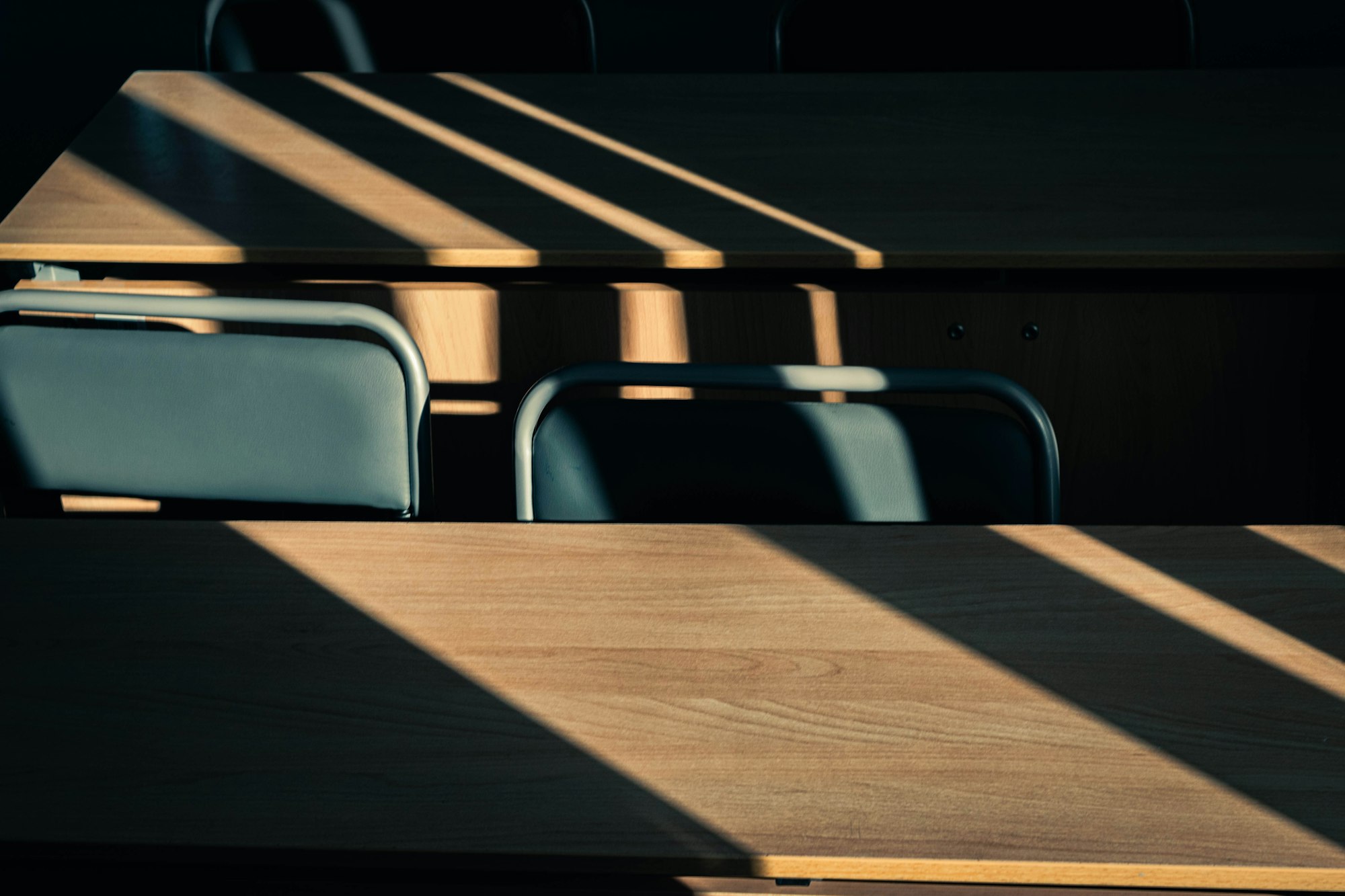 Morning light falling through blinds across two wooden desks