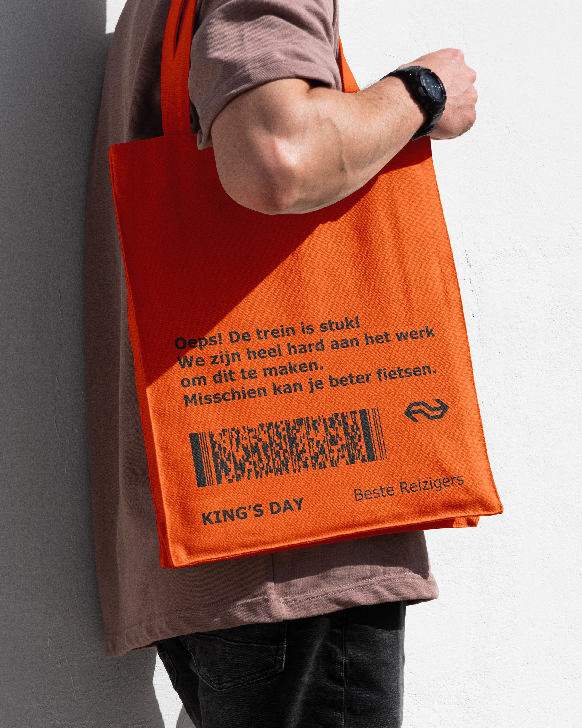 A person holding an orange tote bag with Dutch text and NS logo