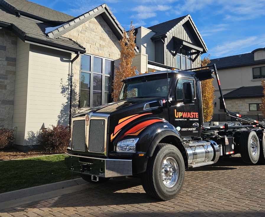 Truck unloading an UpWaste dumpster container outside a warehouse building