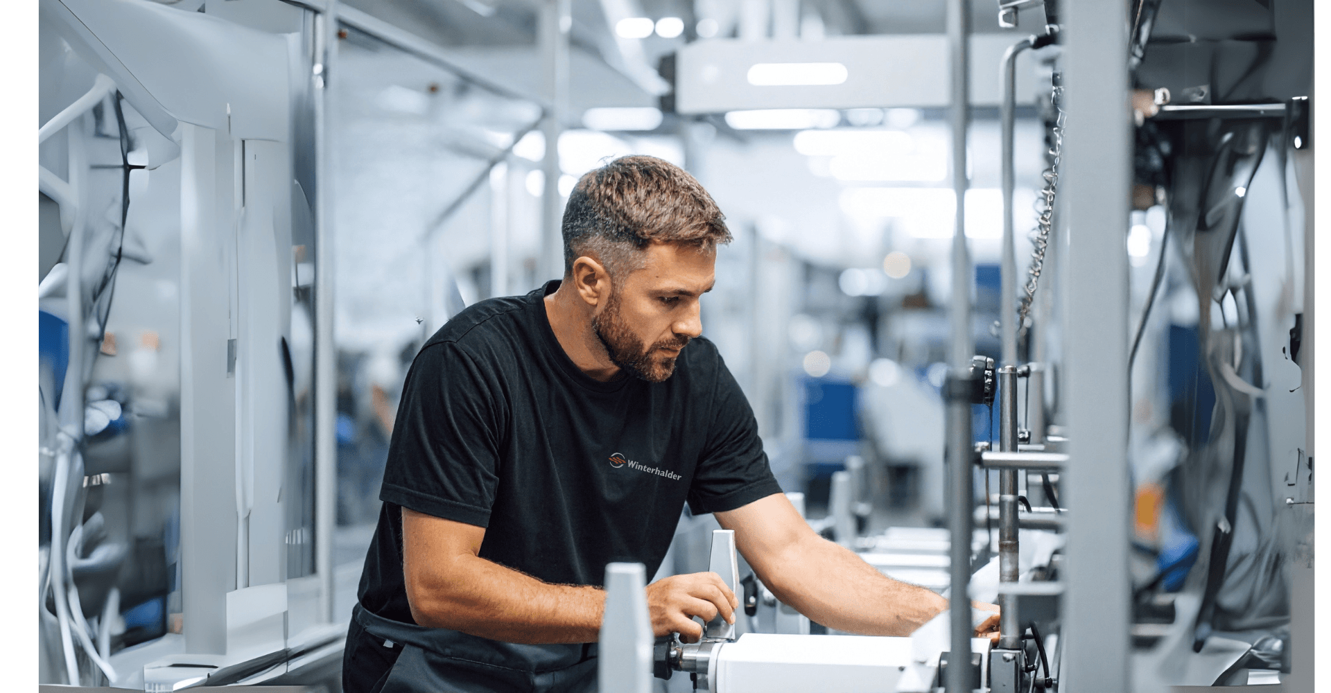 Ein Mann in einer Werkstatt konzentriert sich auf Maschinen, trägt ein schwarzes Hemd und ist von Geräten umgeben.