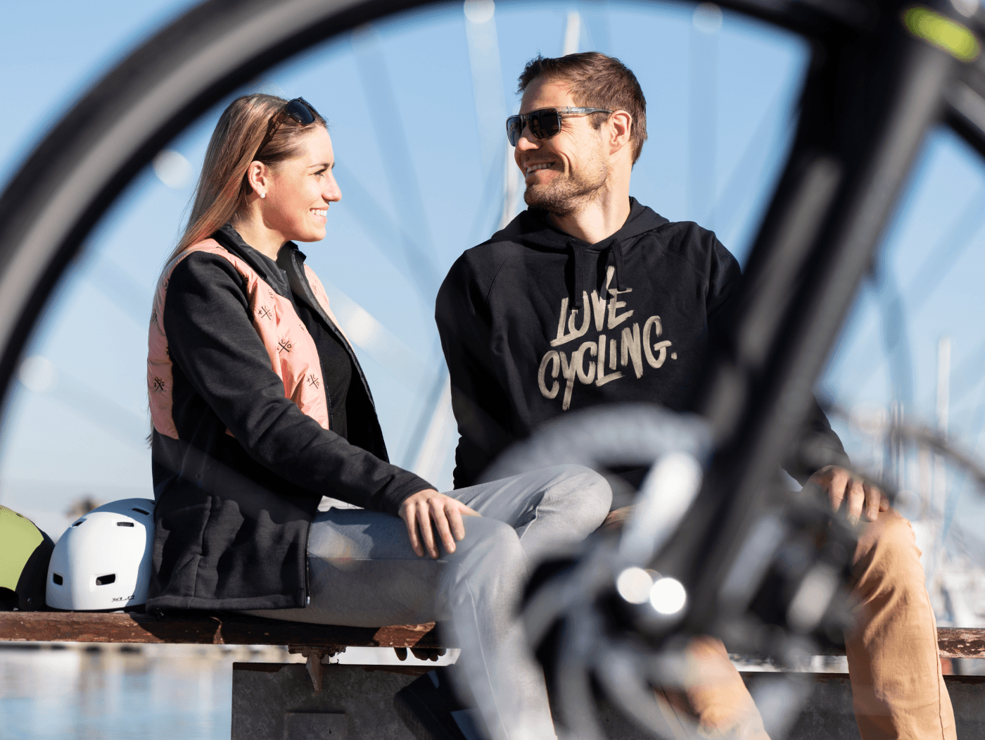 a woman and a man are sitting with XLC clothing in front of a bicycle