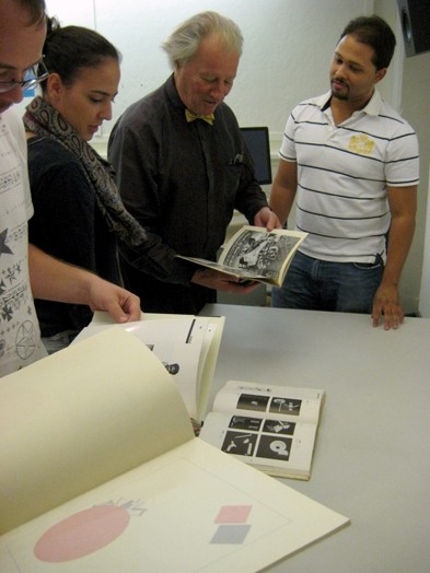 A photo of a group of people looking trough some artbooks.