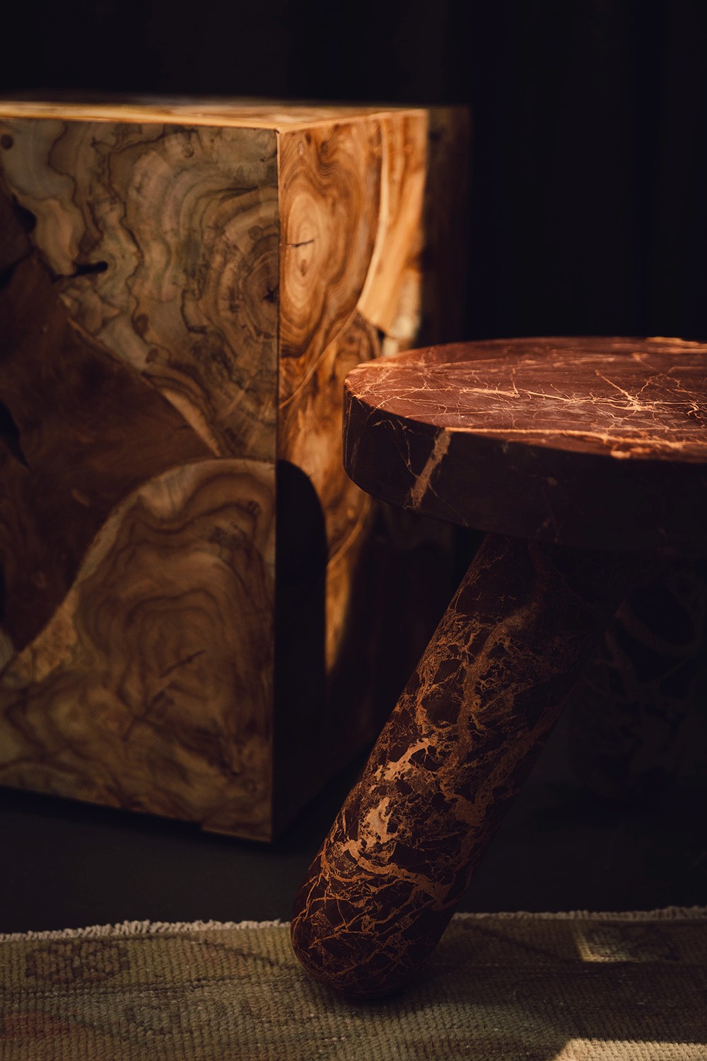 A warm tone wood coffe table sits on a decorative rug adjacent to a stone marble bench in the greenroom of Particle Studio in Seattle, WA