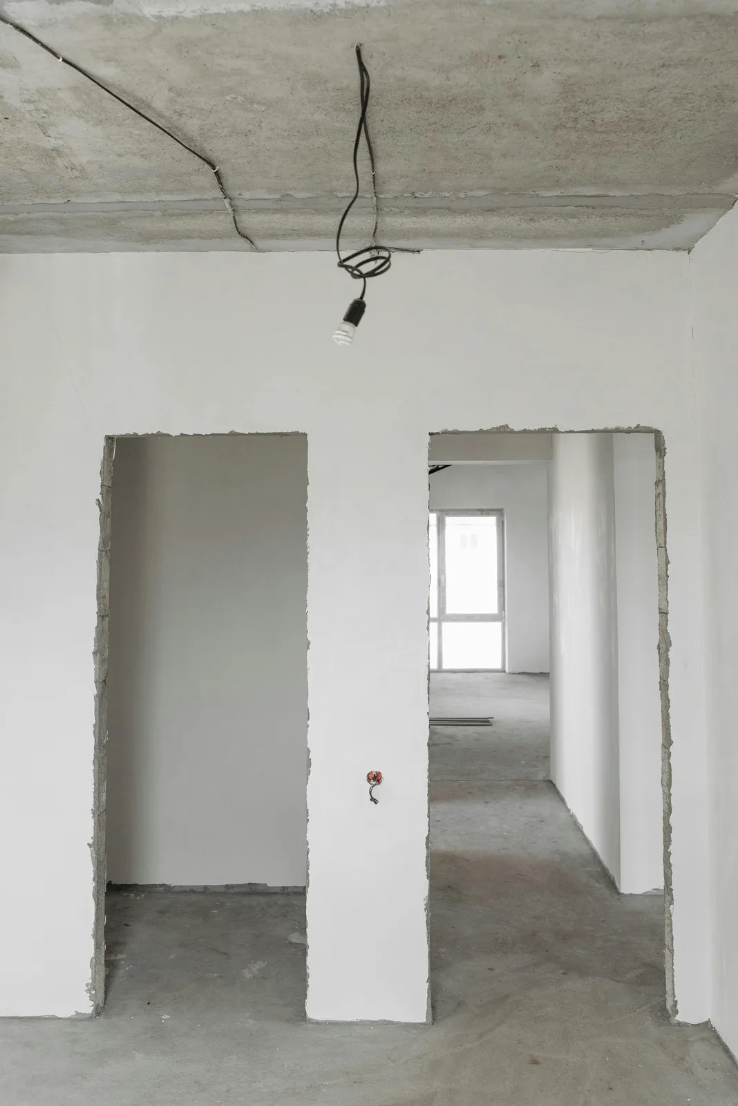 Unfinished interior with plastered walls and exposed ceiling wires