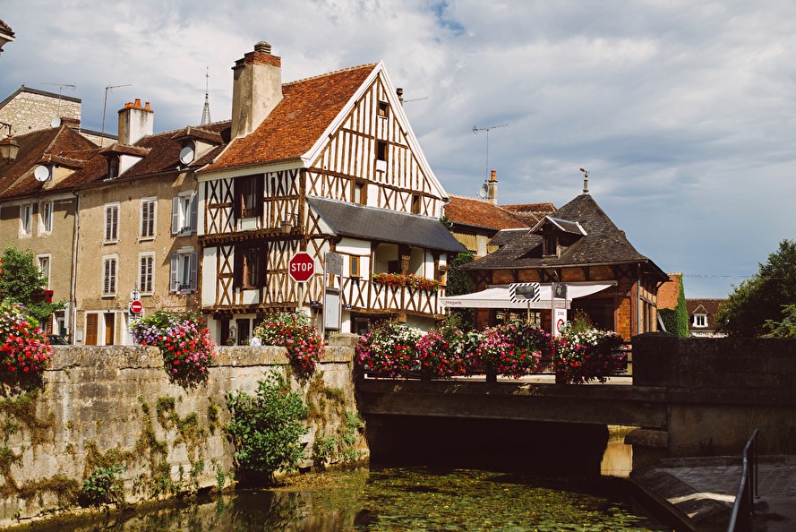 Vue pittoresque d'une ville française avec maisons à colombages, fleurs et canal. Tourisme en France.