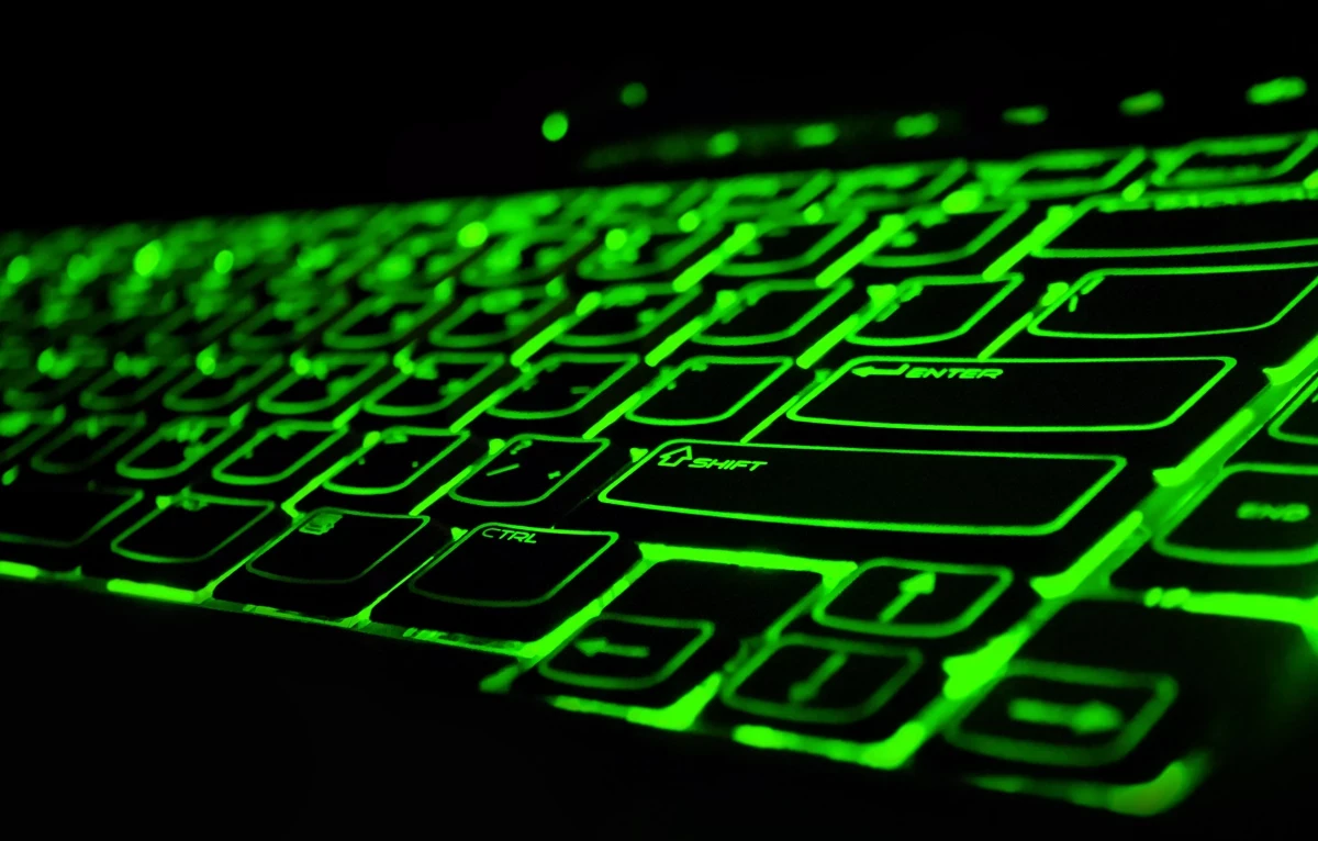 A closeup of a computer keyboard glowing with a green backlight