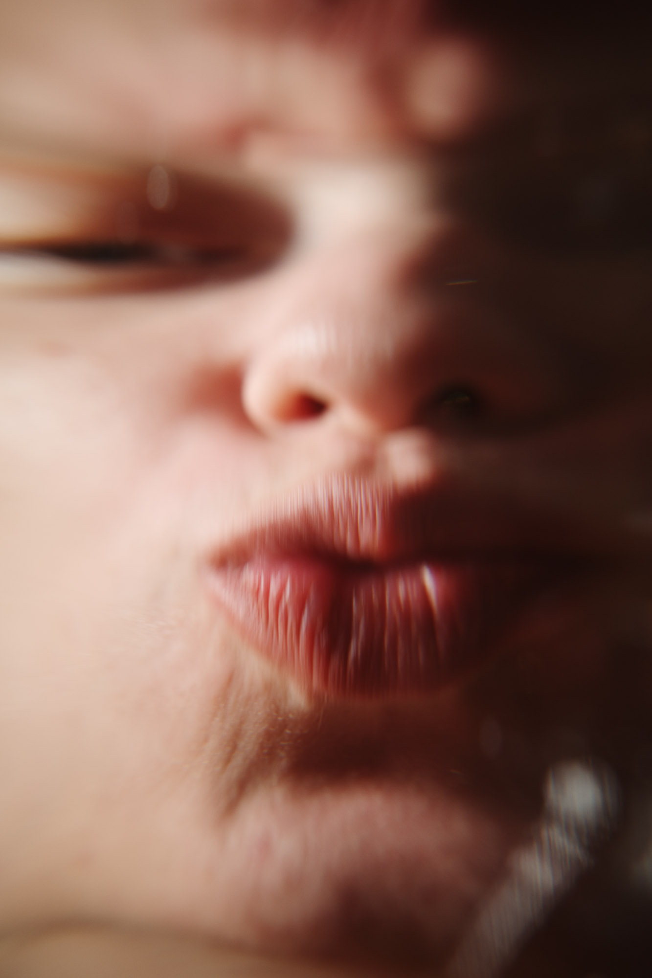 A close-up image shows a face pressed against glass, distorting facial features and creating playful, exaggerated expressions.