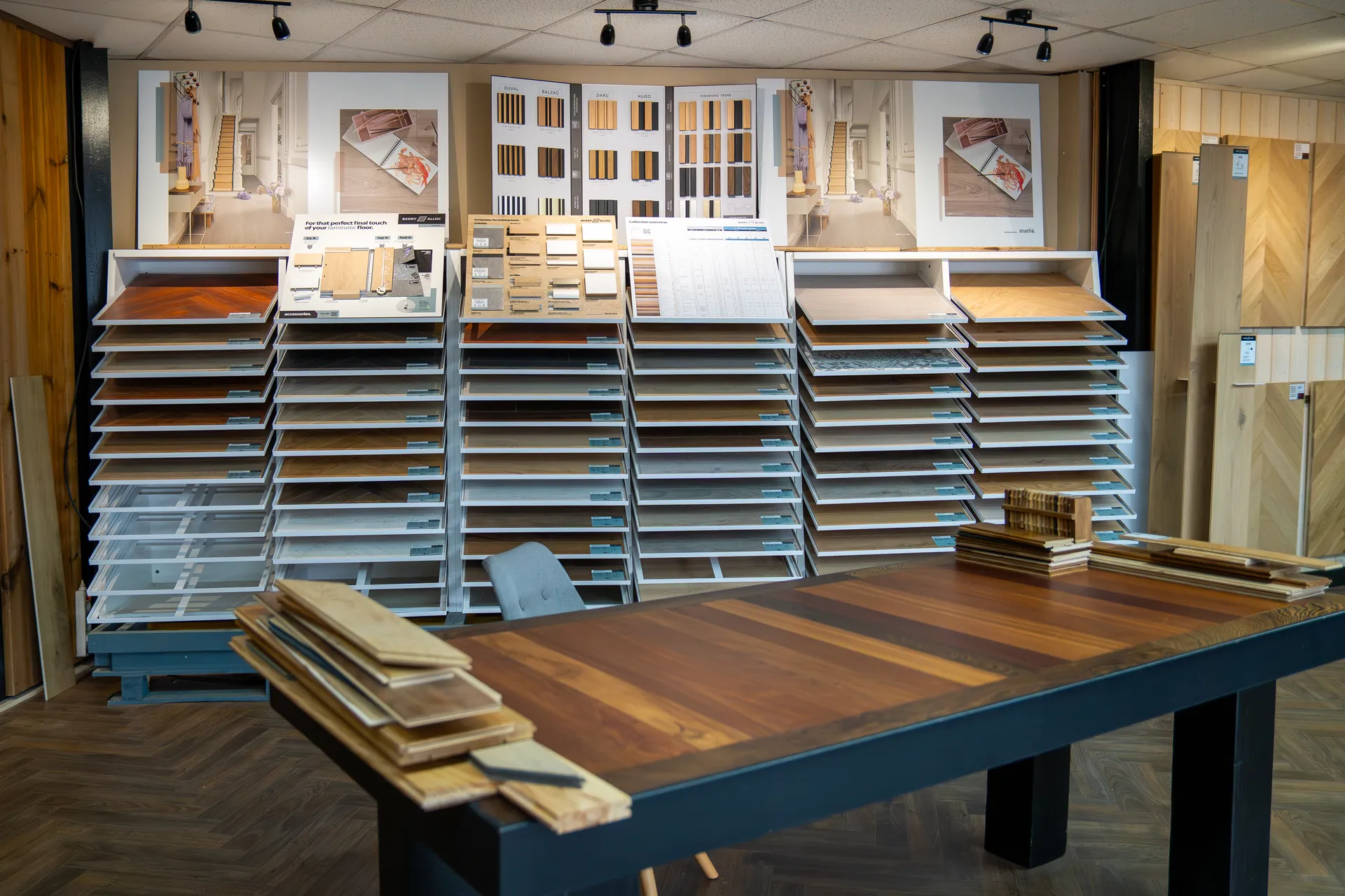 Échantillons et lames de parquet exposés sur la grande table de présentation du showroom Aliénor Parquet à Mérignac