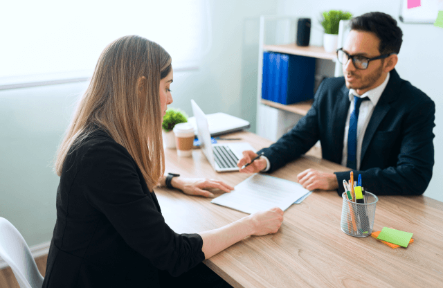 Two colleagues discussing data on a laptop screen.