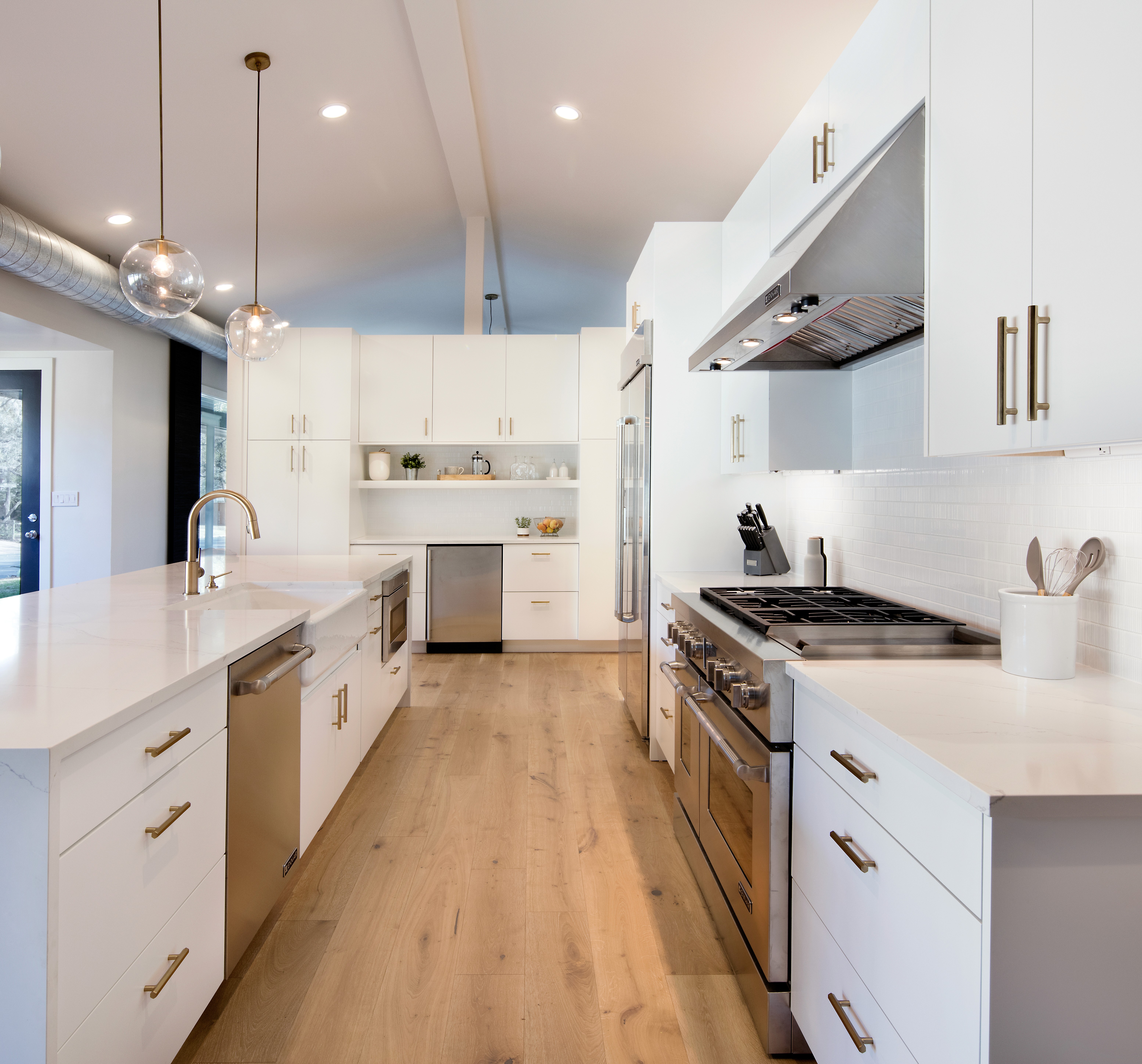 Custom white kitchen with brass hardware and a professional range.