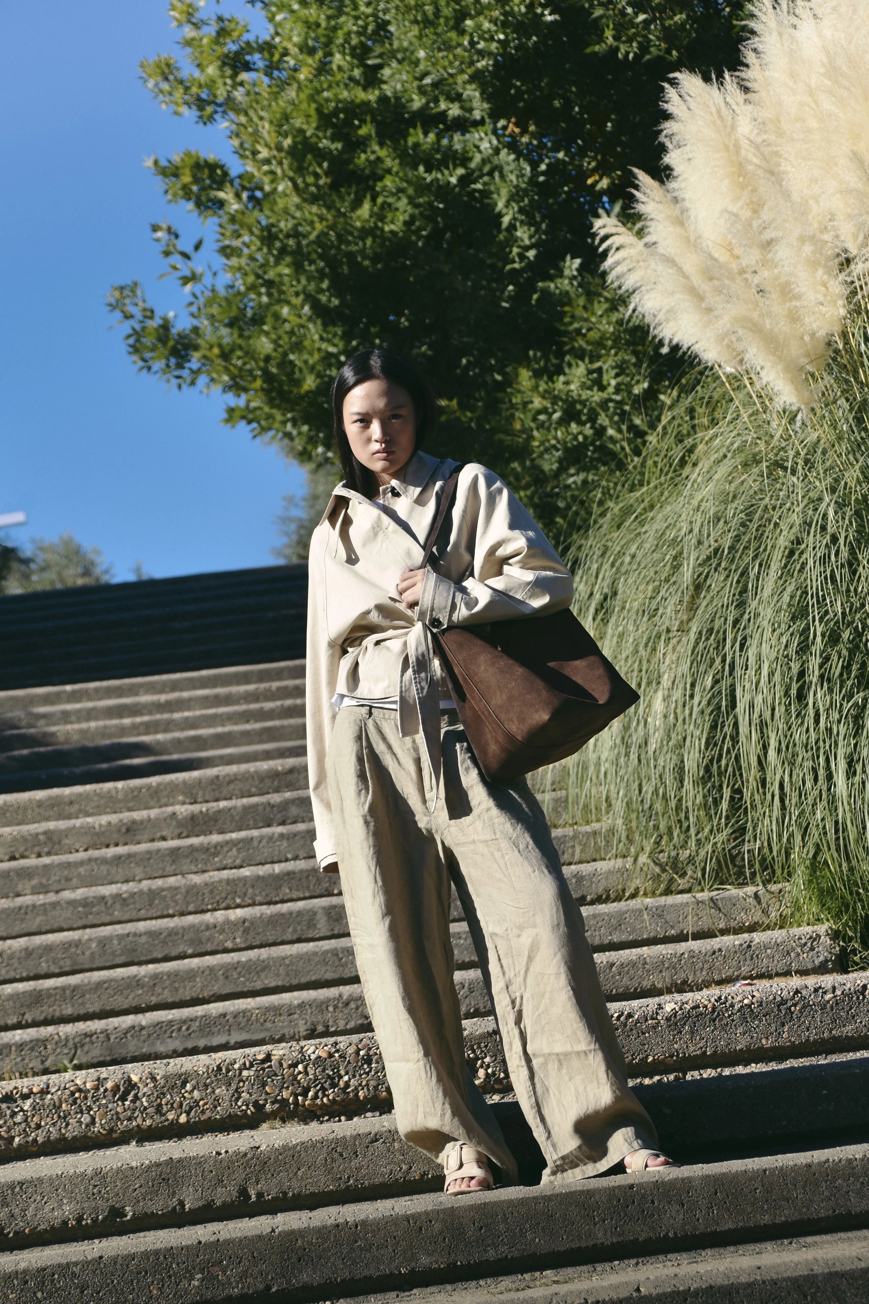 Modelo posando en unas escaleras brutalistas naturalistas con un bolso de la marca de bolsos artesanales Lulia Spain
