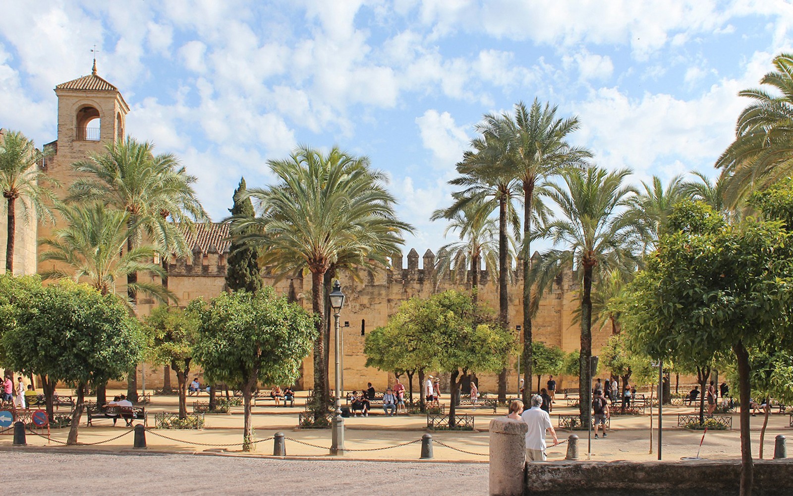 Patio de la Mezquita-Catedral de Córdoba con palmeras y visitantes explorando.