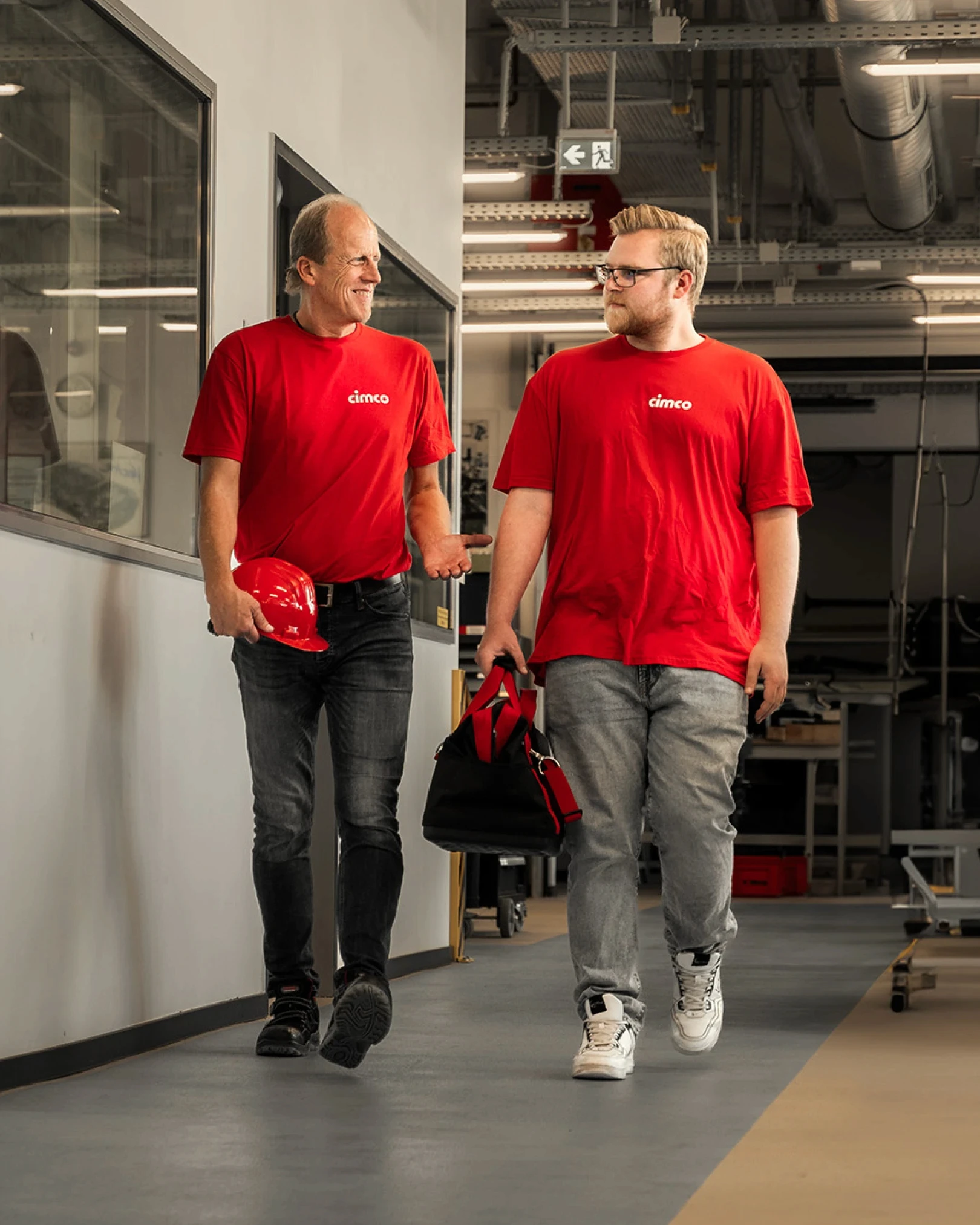 Two men with red shirts walking down an aisle