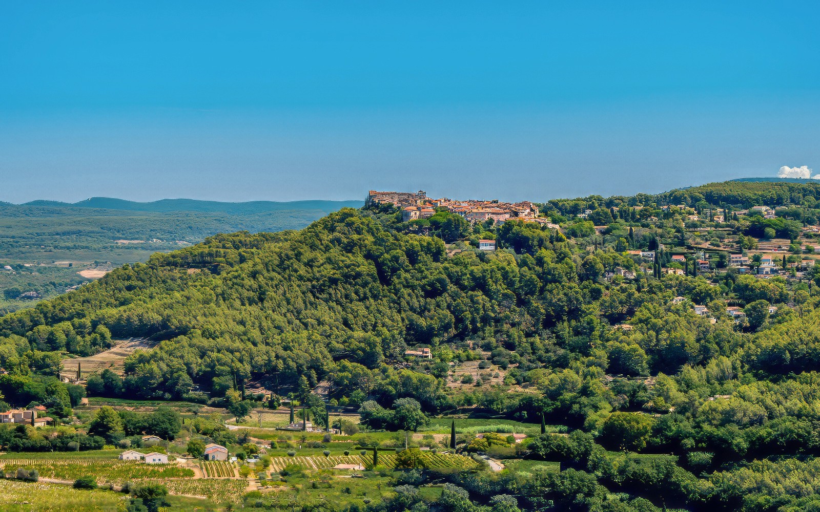 Hilltop village surrounded by vineyards in Bandol, France, under a clear blue sky.