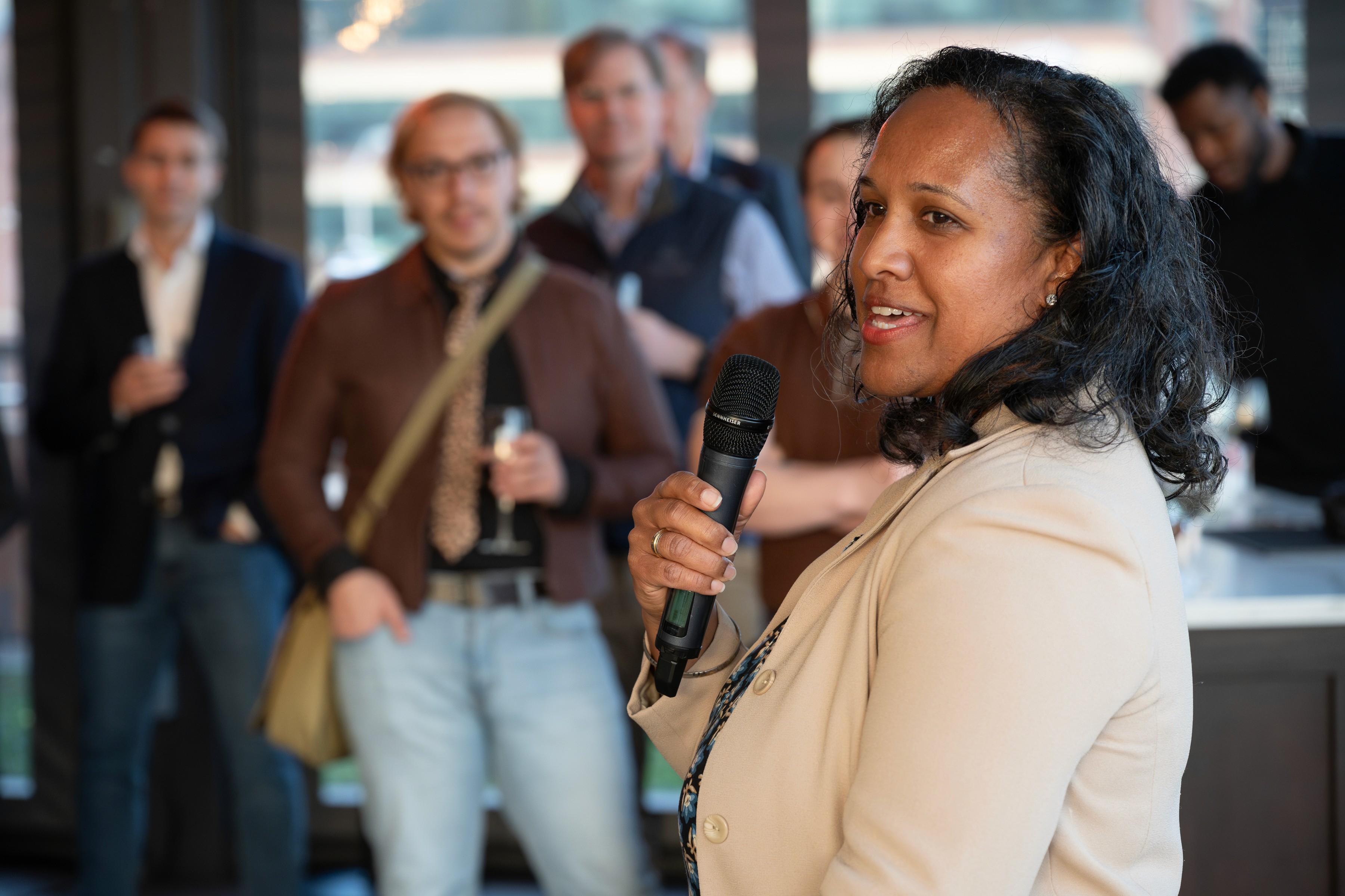 A woman holding a microphone speaking to a group of peopl