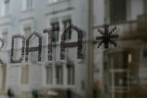 Close-up of the word “DATA” displayed on a glass window, with a blurred city building reflected in the background.