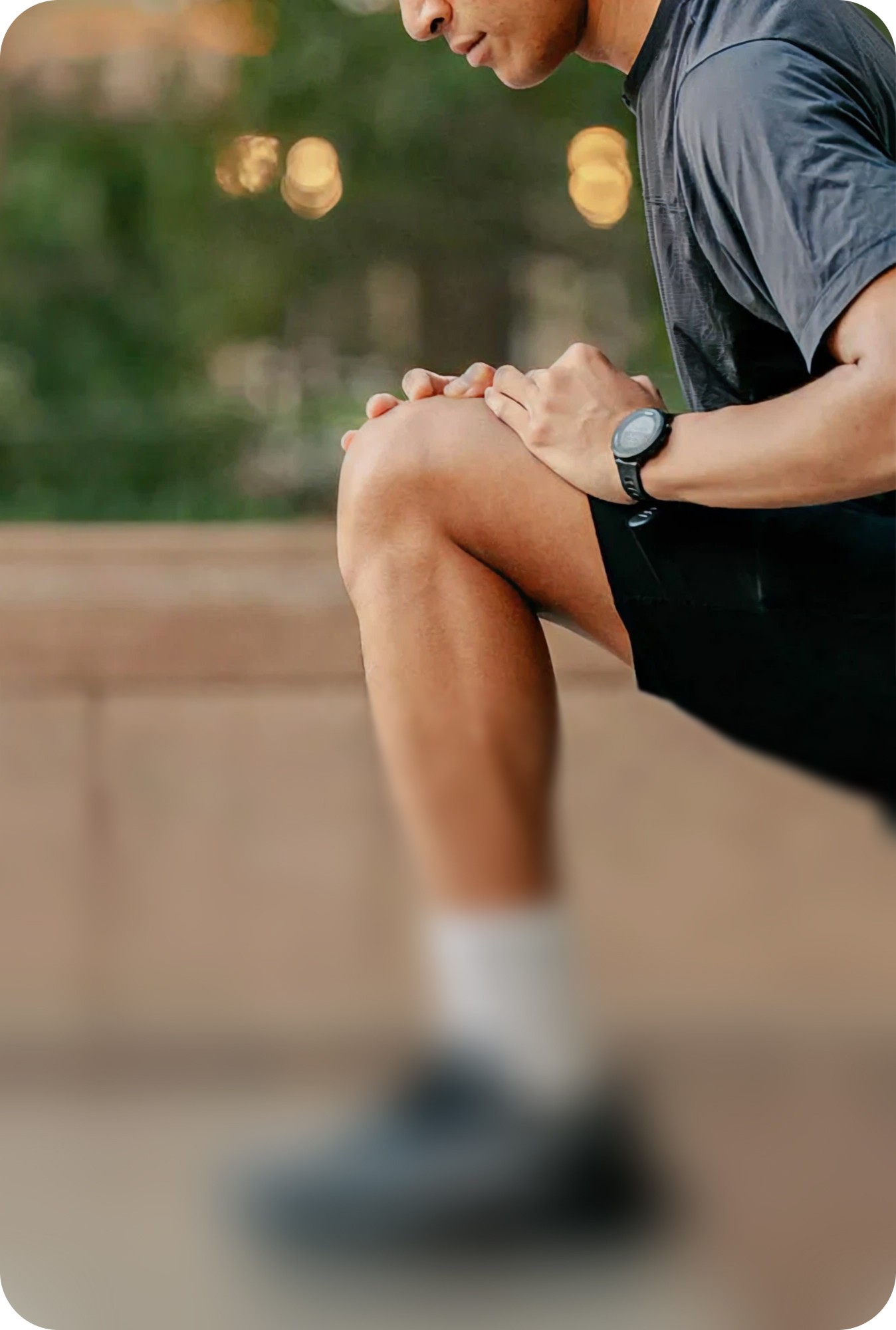 A person sitting on the ground outdoors while stretching their legs during a workout.