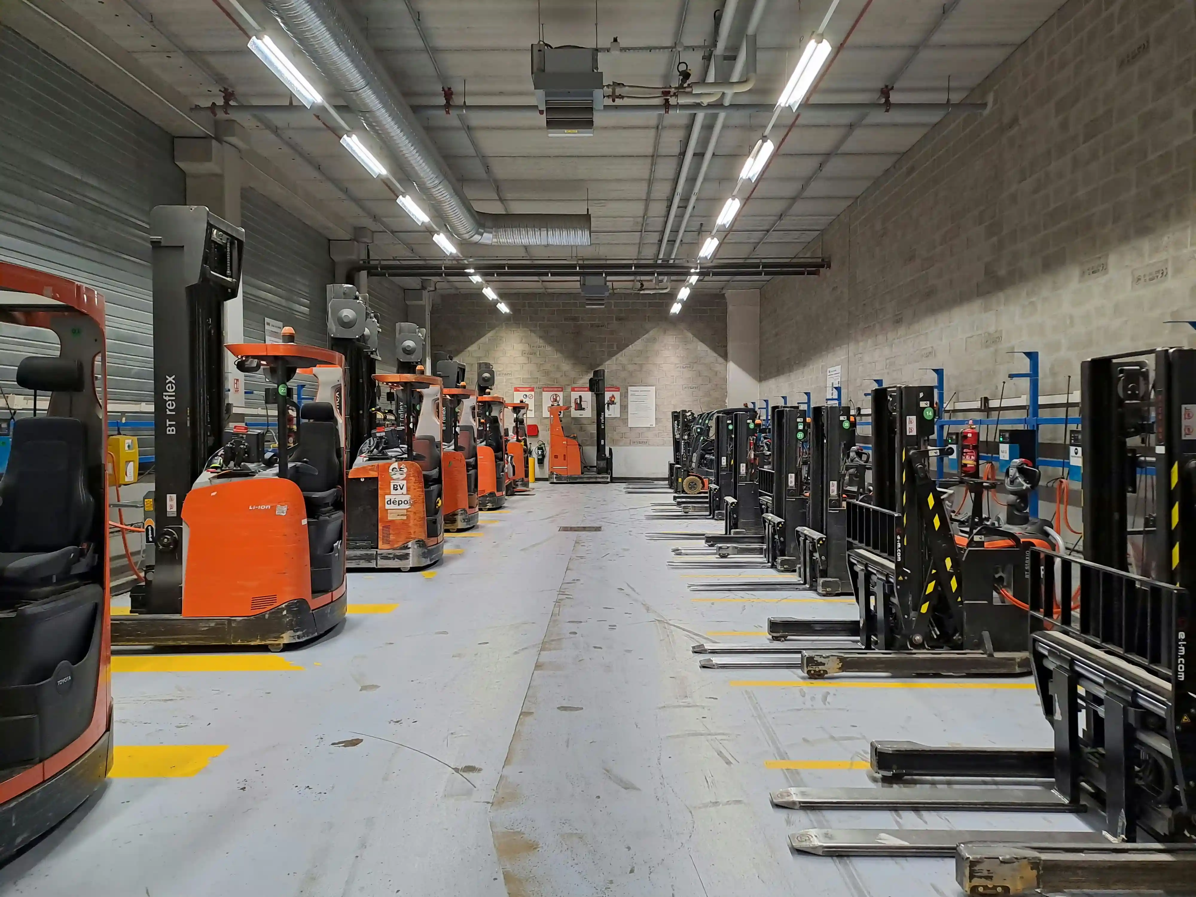 An interior shot of a 3PL warehouse with bright orange forklift trucks lined up