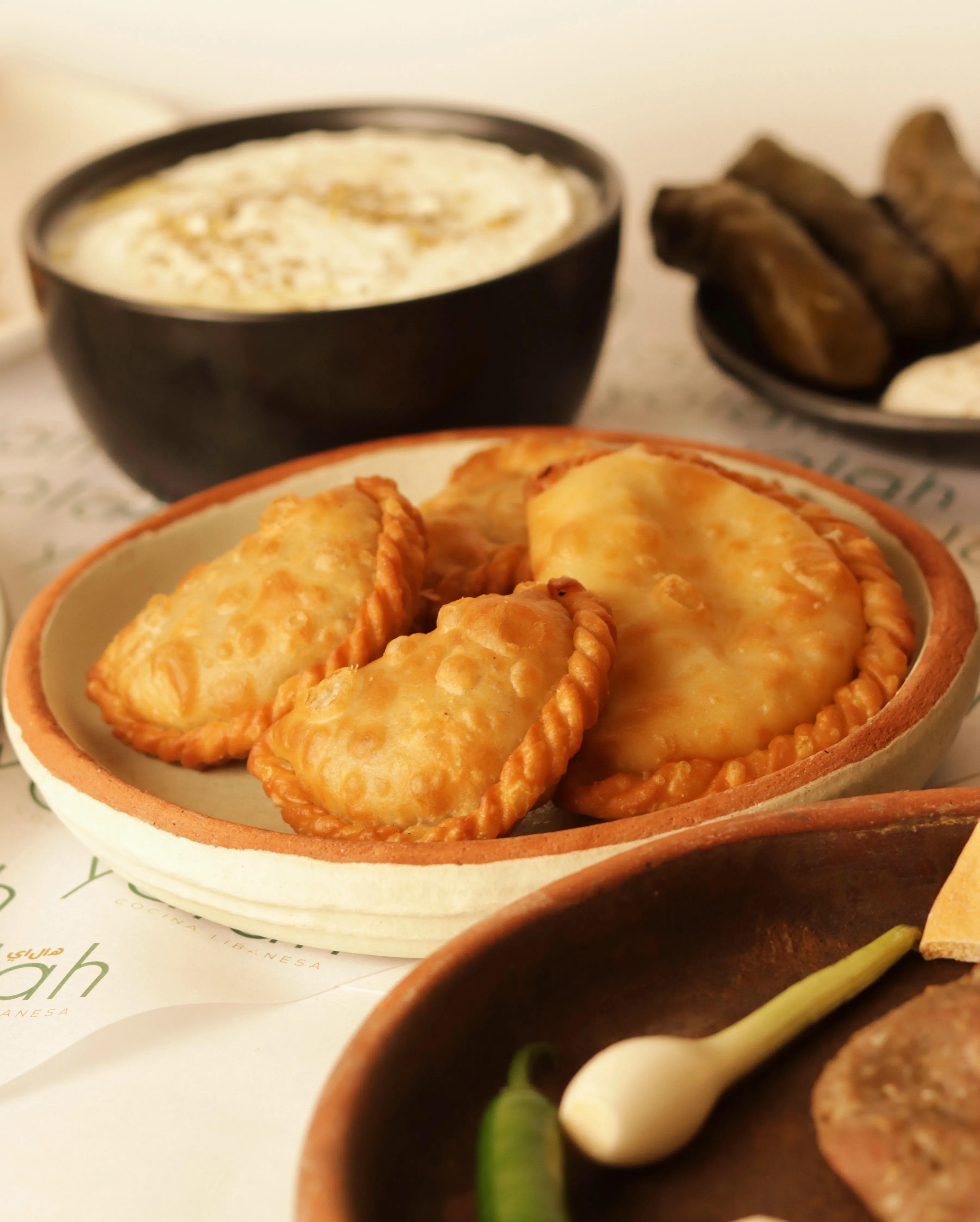 Empanadas libanesas con salsa de ajo en fondo cálido.
