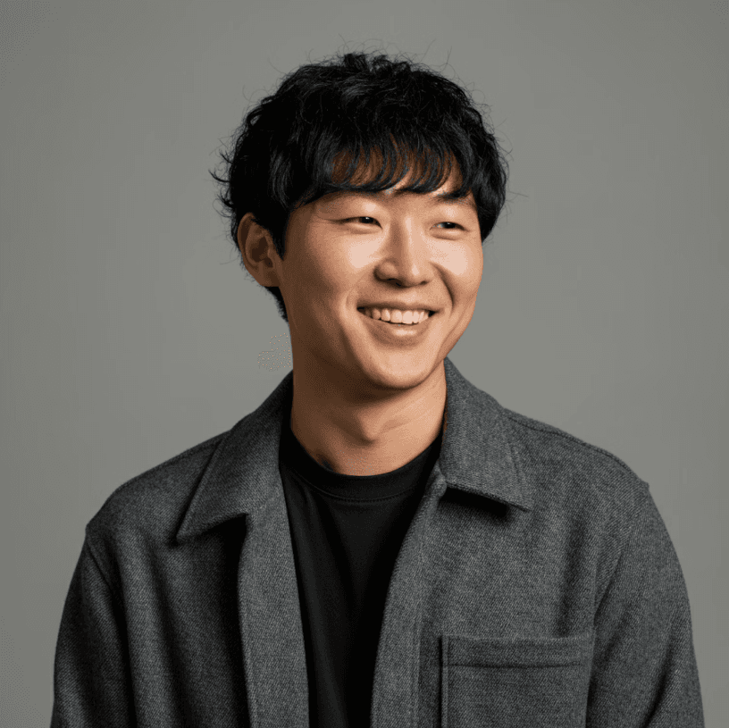 Smiling young man in a dark jacket on a gray background.