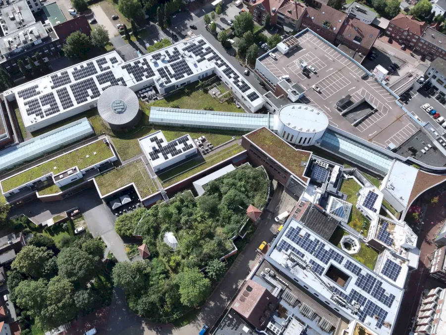 Luftaufnahme eines Gebäudekomplexes mit Gründächern und Solaranlagen