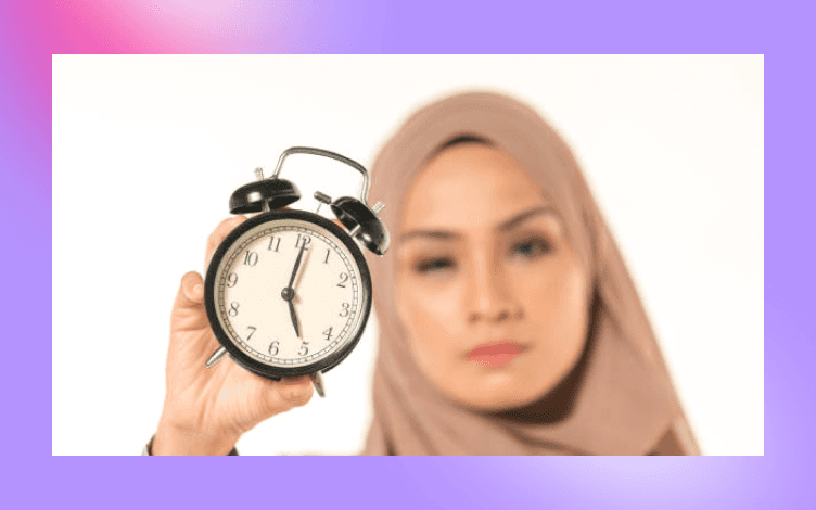 Alarm clock in focus with a contemplative woman blurred in the background, representing the discipline of structuring daily routines around prayer times.