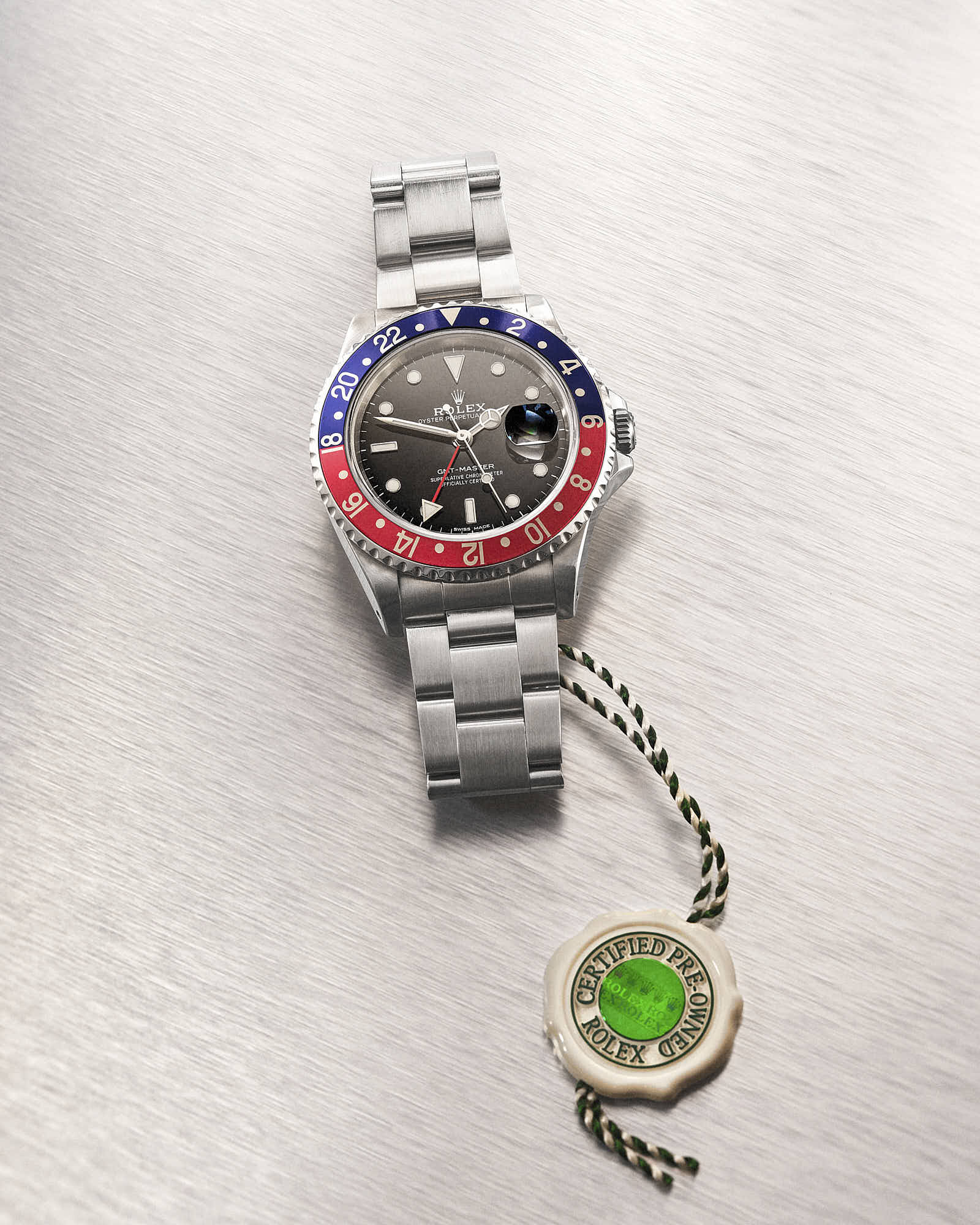 Luxury Rolex GMT-Master II Pepsi watch with stainless steel bracelet on brushed metal background.