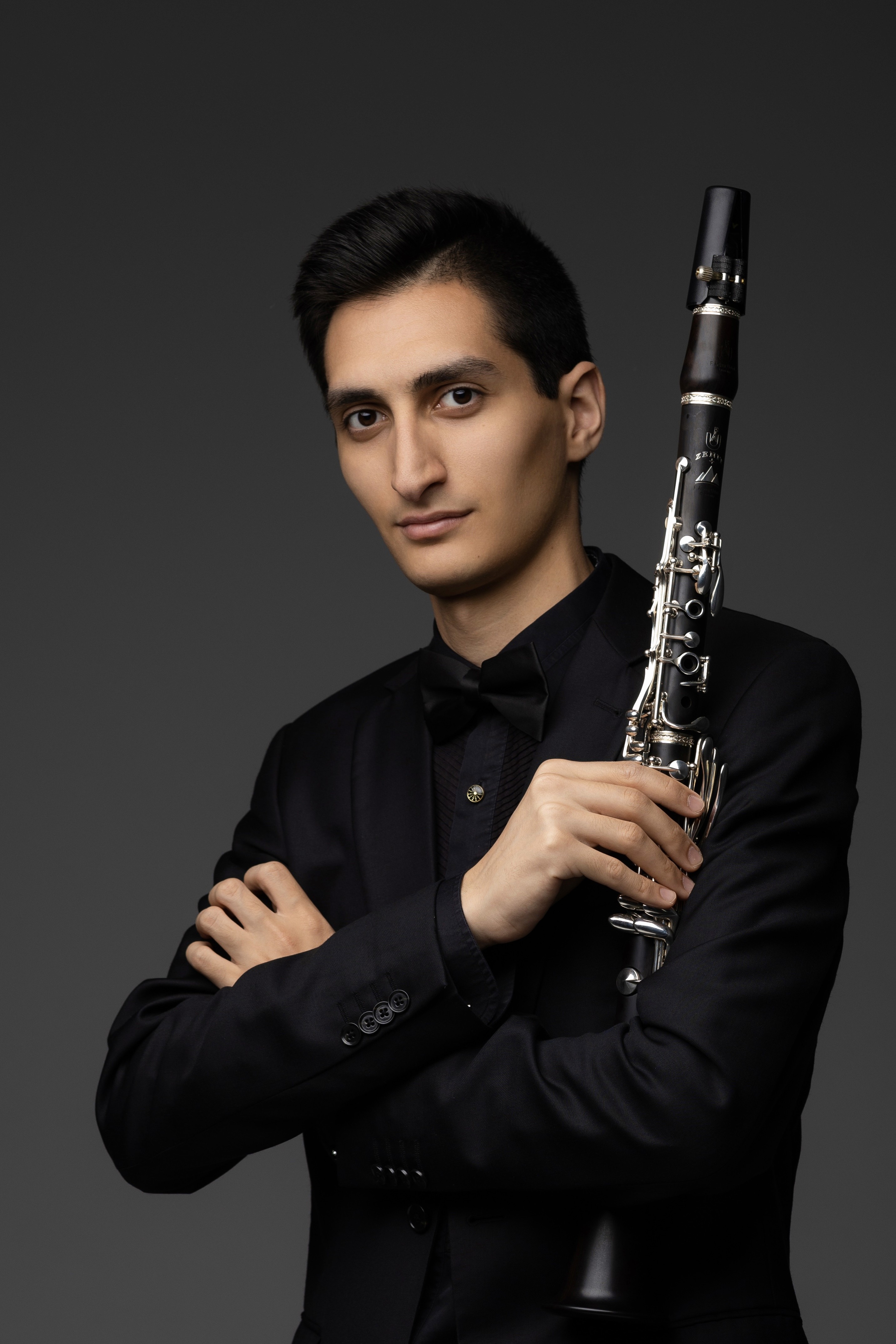     Erik Mirzoyan holding a clarinet in a dark studio portrait