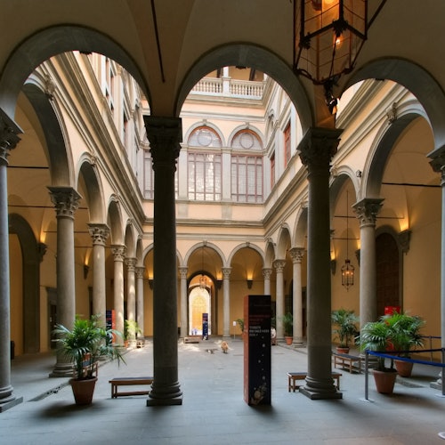 A man holding a child points at an ornate religious triptych encased in glass at a museum. The child has a pacifier.