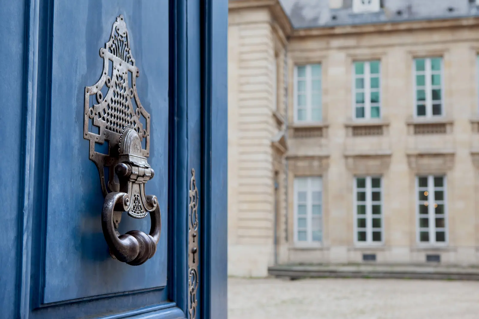 Historic blue doorway opening towards a traditional estate building, symbolising inheritance, continuity, and the transfer of wealth across generations.
