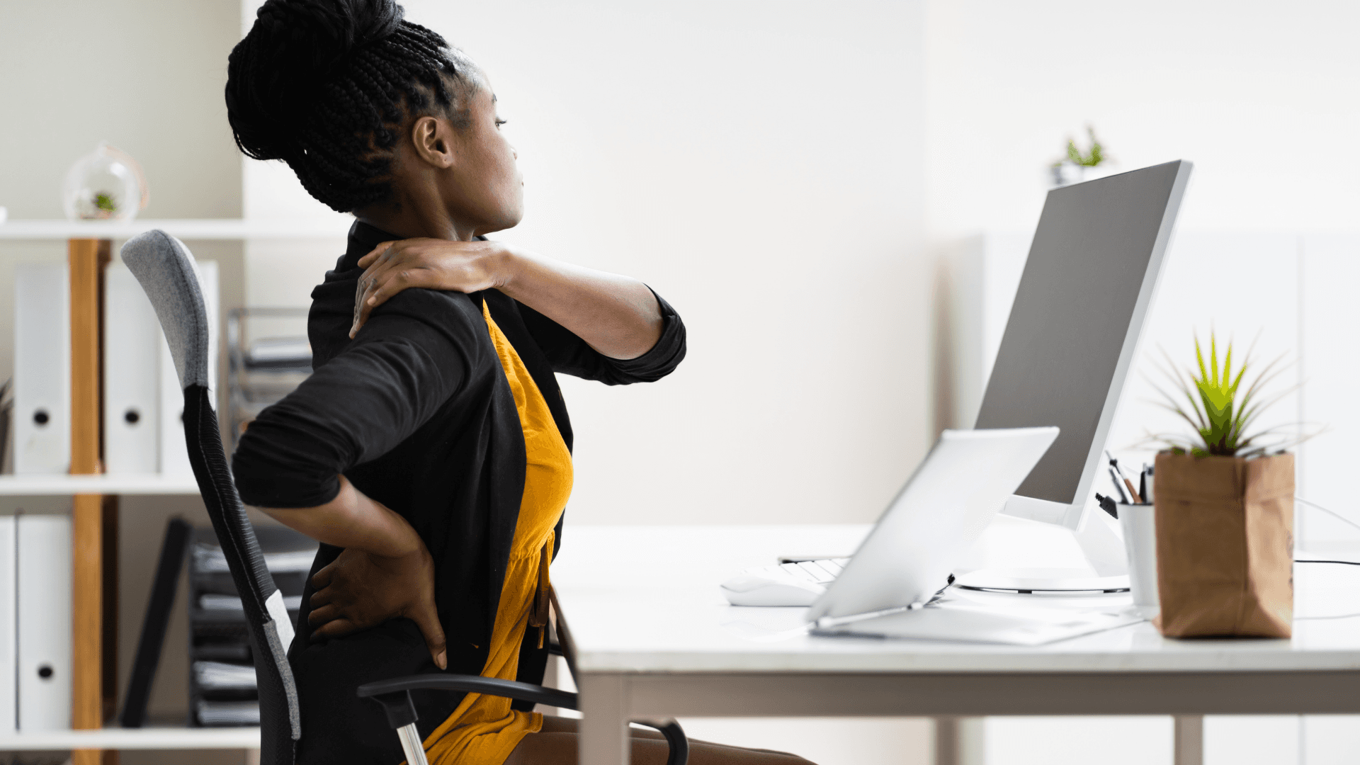 A winding road cuts through rocky terrain, surrounded by patches of green grass and illuminated by sunlight.