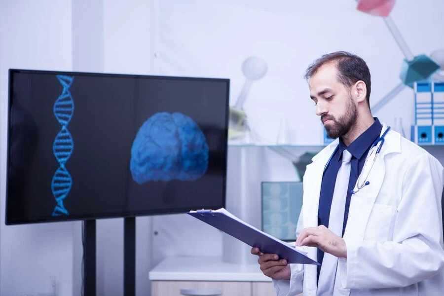 young doctor with clipboard his hands standing by monitor with brain