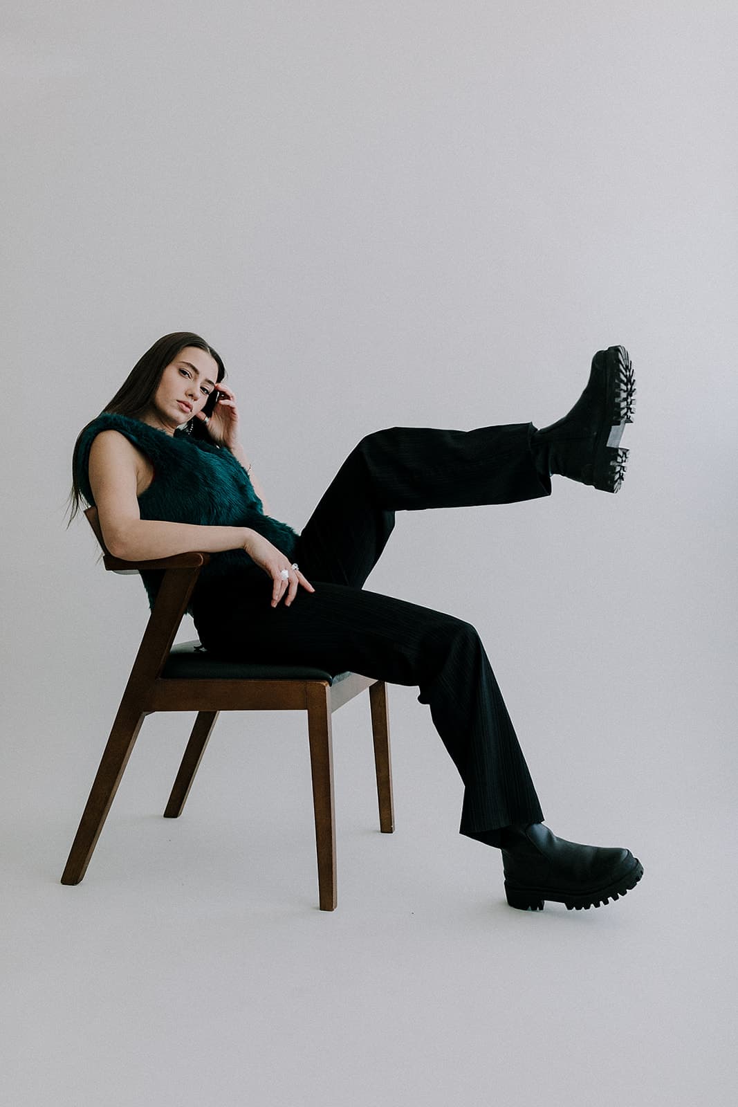 A model lounges in a chair with one leg up, captured during a fashion shoot in Revelator Studio, a natural light studio in Shreveport.