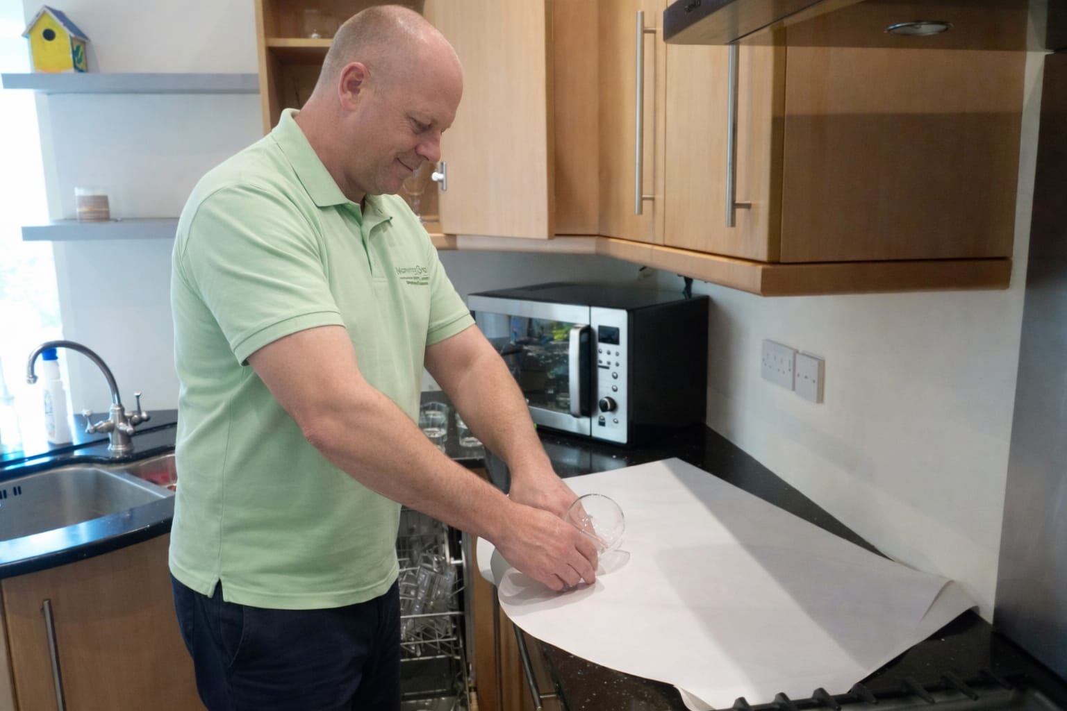 A professional mover from Moving On Removals expertly packing glassware in a Plymouth kitchen using premium protective materials.