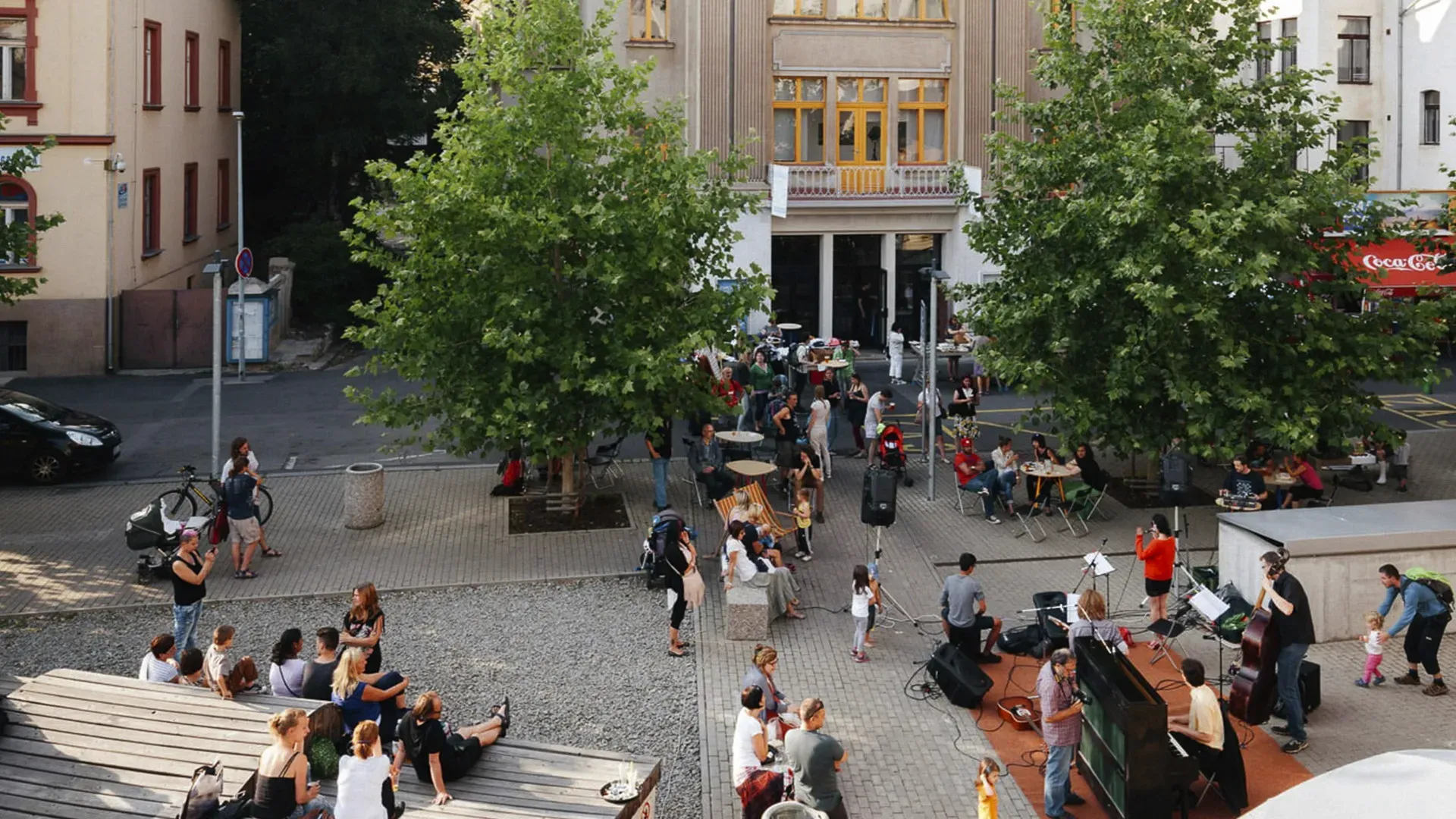 Živé setkání lidí na náměstí s hudbou. Ilustrace oživení veřejného prostoru a posilování vztahů.