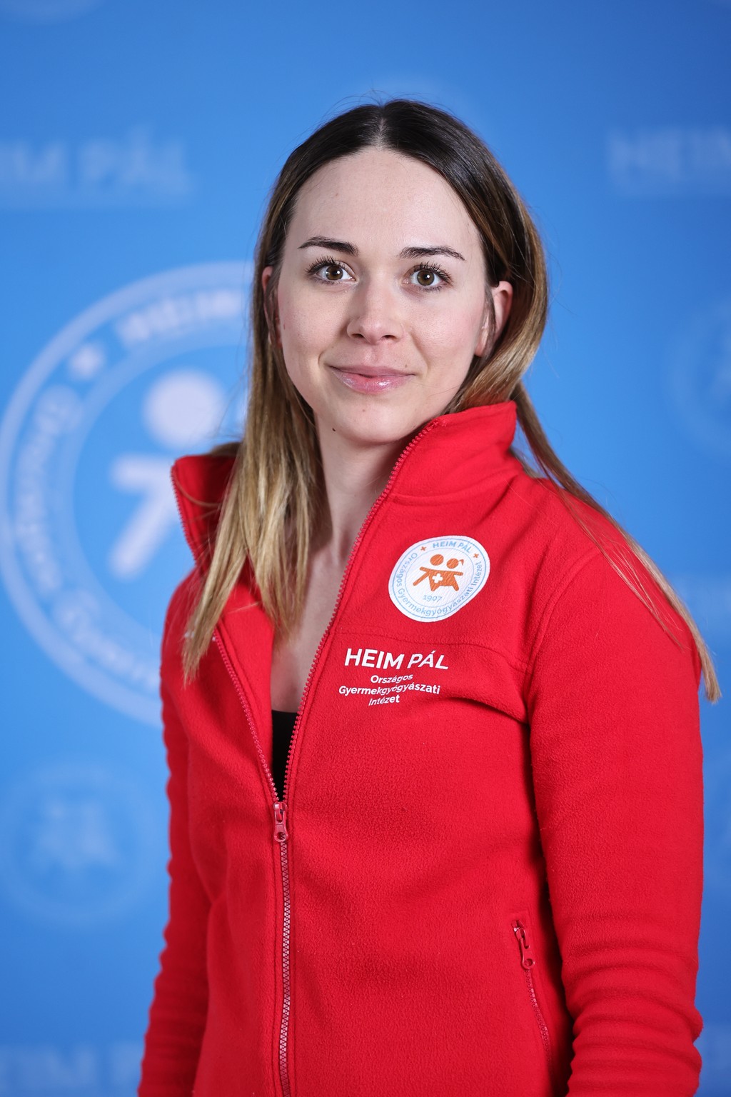 Hosszú szőke hajú nő piros kardigánban