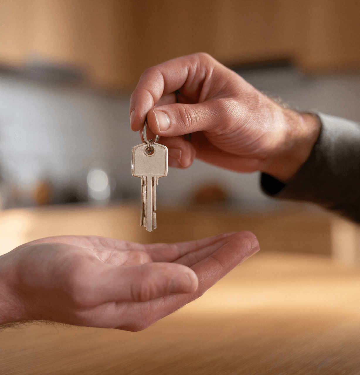 A close-up of a host's hand giving keys to a guest, symbolizing the start of a short-term rental and the critical need for comprehensive Airbnb insurance to protect the property and host.