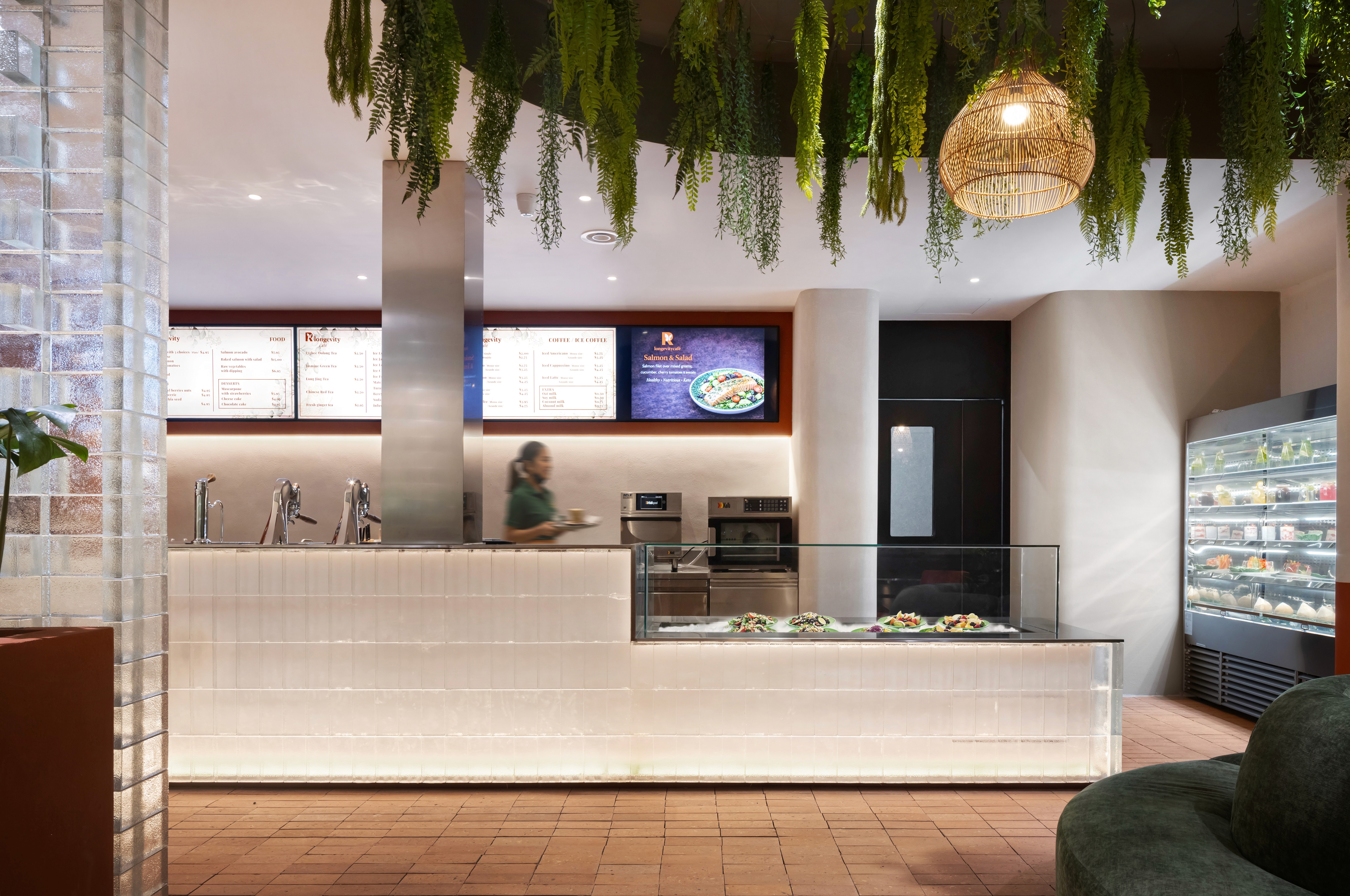 Service counter with glass block cladding, stainless steel service fittings, and clay tile flooring, robust front-of-house detailing designed for high turnover and simplified maintenance