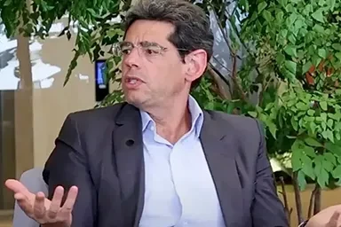 Três pessoas conversam ao ar livre, cercadas por plantas verdes e uma atmosfera relaxante.