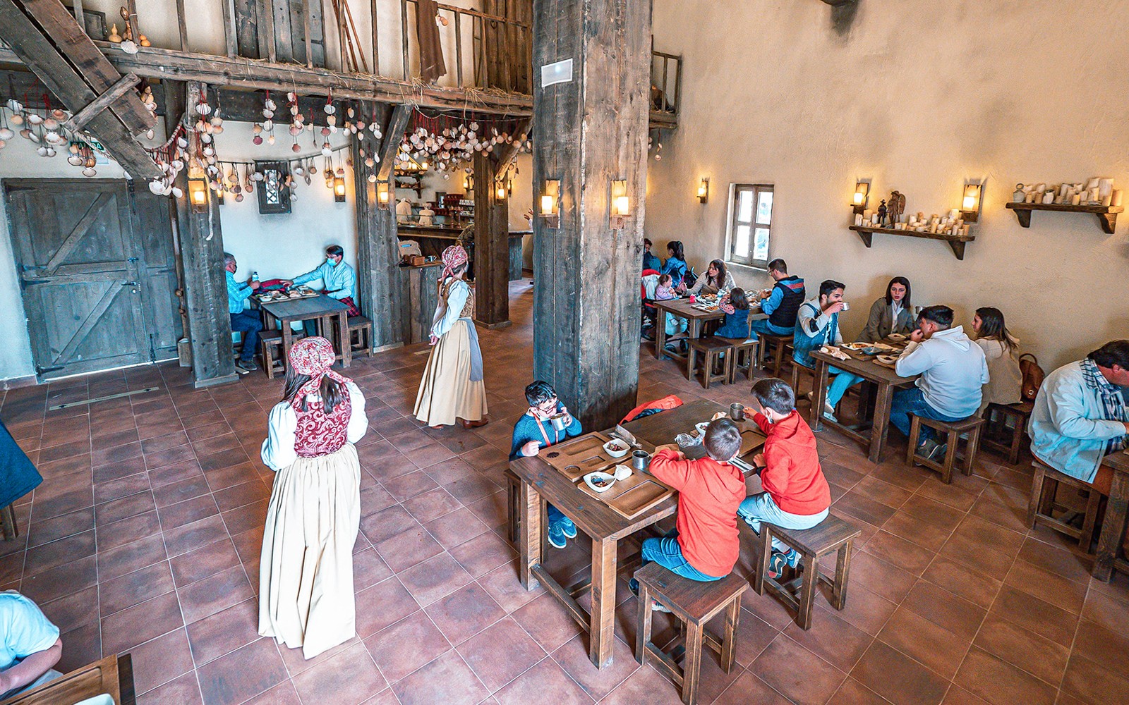 Visitors dining in a rustic medieval-themed restaurant at Puy du Fou España.