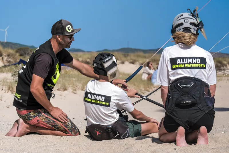 Explora Watersports Tarifa Kitesurf-Instruktor, der Schüler bei einer Kontrollsession am Strand anleitet.