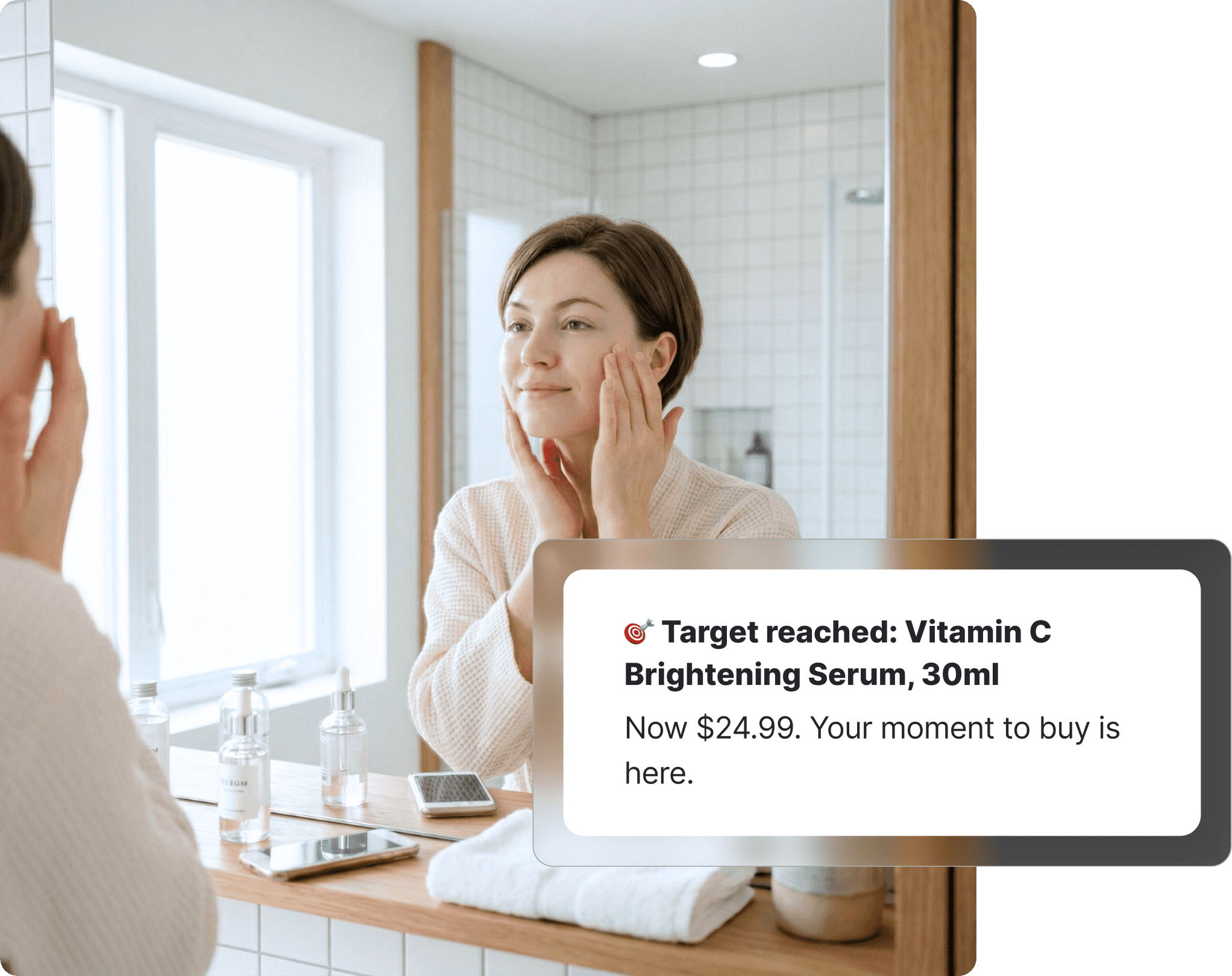 Woman in a waffle robe applying skincare in front of a bathroom mirror, receiving a Priceline target price notification for a vitamin C serum on Whisprice, with serum bottles and a phone on the counter.